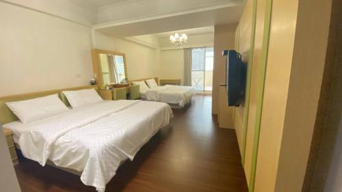 een hotelkamer met 2 bedden en een televisie bij 美達民宿 in Donggang