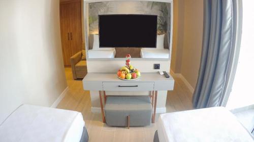 a room with a television and a table with a bowl of fruit at Alessia Hotel in Side