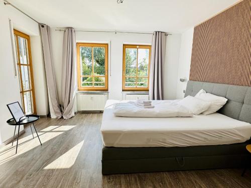 ein Schlafzimmer mit einem Bett und einem Tisch und Fenstern in der Unterkunft LIKE HOME, cozy apartment, 2 bedrooms, Netflix, 55" TV, balcony, parking, self-check-in in Penzberg