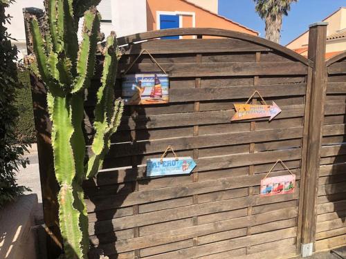un cactus e segni su una recinzione di legno di Pavillon 3 chambres avec véranda et climatisation. a Sorède