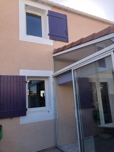 une maison avec deux fenêtres et une porte coulissante en verre dans l'établissement Pavillon 3 chambres avec véranda et climatisation., à Sorède