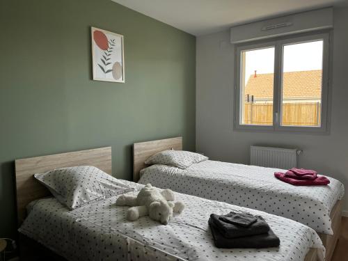 2 camas individuales con un osito de peluche sentado sobre ellas en Maison les coquelicots en Garennes-sur-Eure