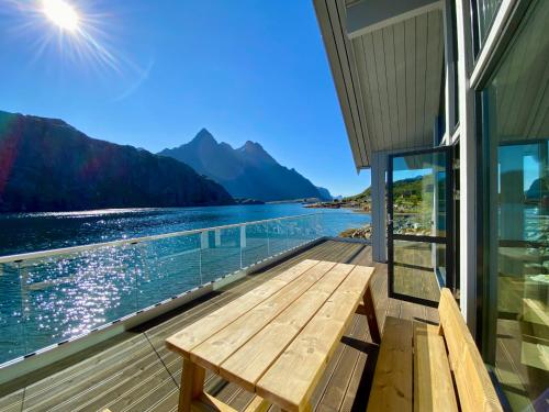 a wooden bench on a balcony with a view of a lake at Beachfront Paradise Lofoten in Bøstad