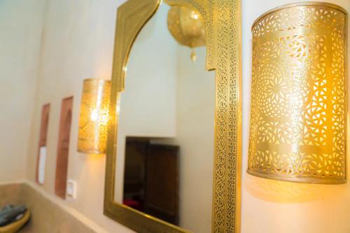 a gold lamp on a wall next to a mirror at Riad Dar Zaouia in Marrakech
