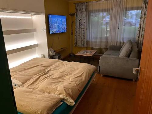 1 dormitorio con cama, sofá y TV en Schnuckeliges Appartement in Prien am Chiemsee, en Prien am Chiemsee