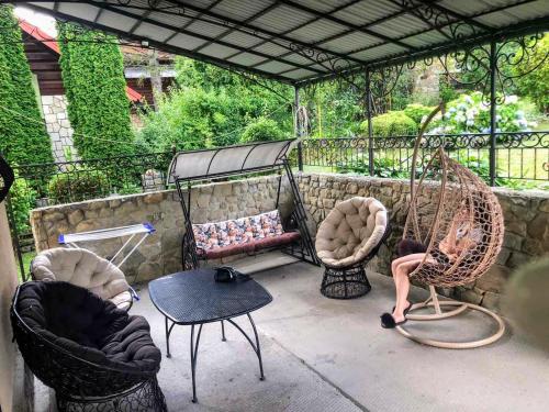 un patio con sillas, un columpio y una mesa en Cottage "Lure" en Yaremche