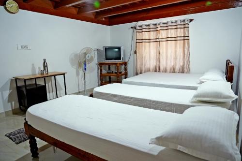 a room with three beds and a tv and a window at Hazel Retreat - Full Home & Coffee Estate in Chikmagalūr