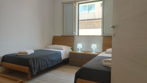 a bedroom with two beds and a window at MareVivo Marzamemi in Marzamemi