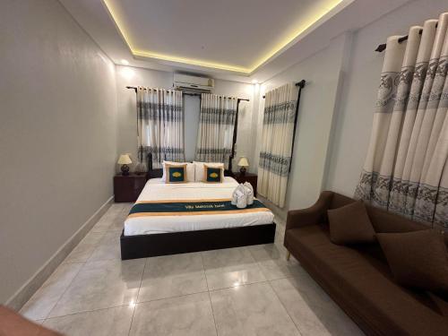 a bedroom with a large bed and a couch at Villa Mahasok hotel in Luang Prabang