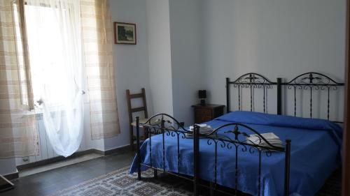 1 dormitorio con cama con sábanas azules y ventana en Typical Sicilian House with Garden in the Historic Center, en Piazza Armerina