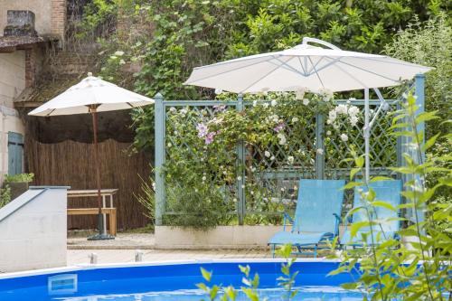 dos sombrillas y dos sillas junto a una piscina en gite de la brasserie, en Saulgé
