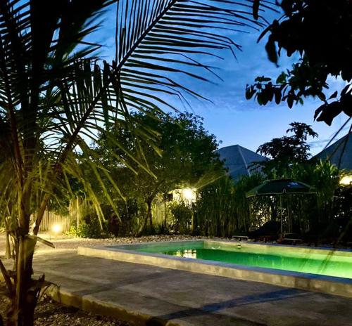 a swimming pool in a yard with a palm tree at Diana Place in Paje
