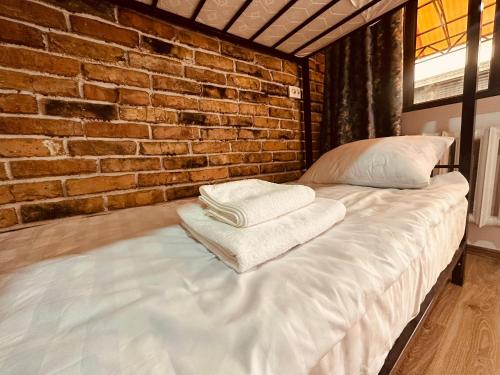 a bed in a room with a brick wall at Kerben House in Naryn