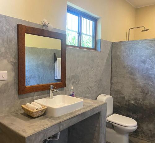 a bathroom with a sink and a toilet and a mirror at Diana Place in Paje