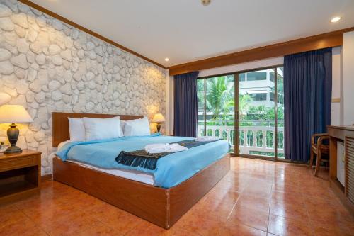 a bedroom with a king sized bed and a balcony at Patong Central Hotel and Apartment in Patong Beach