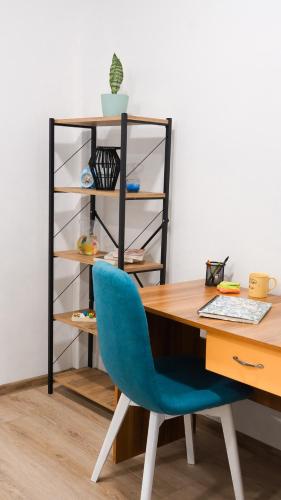 a desk with a blue chair next to a shelf at Apartmani Bubamara Leskovac in Leskovac