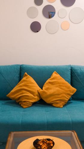 a blue couch with two yellow pillows and a table at Apartmani Bubamara Leskovac in Leskovac