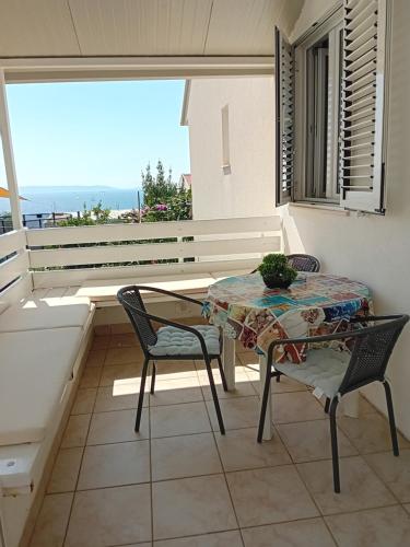 balcón con mesa, sillas y vistas al océano en Spajić Apartments, en Seget Vranjica