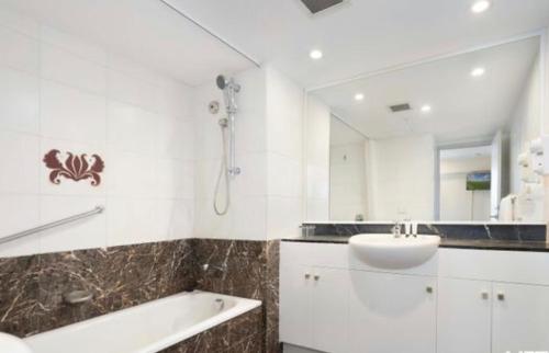 a bathroom with a sink and a tub and a shower at Darling Harbour in Sydney