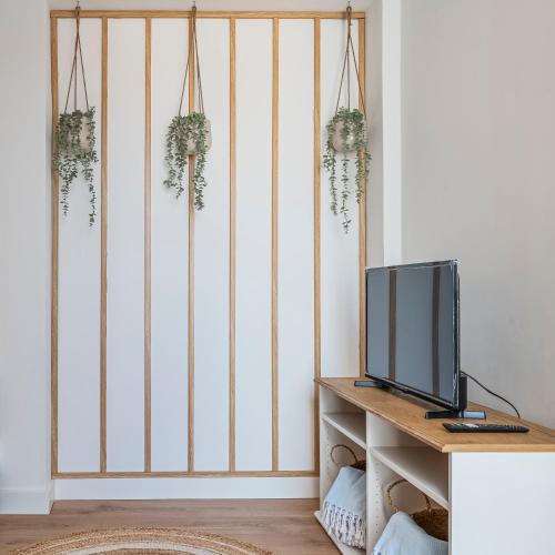 a room with a tv on a wall with plants at Chalet Marias - Parede beach apartments in Parede