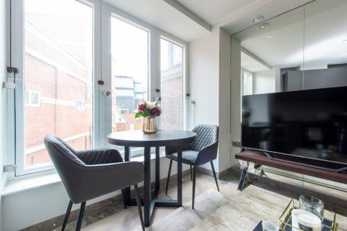 a living room with a table and chairs and a large window at Chic Central Reading 1BR Apt CHRL F2 in Reading