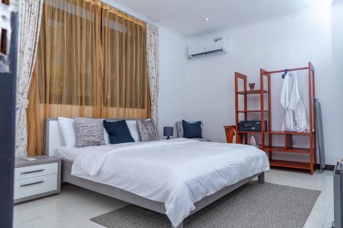 um quarto com uma grande cama branca com almofadas azuis em Upendo Boutique Hotel, Dar es Salaam em Dar es Salaam