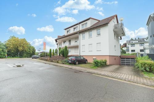 a white building with a car parked next to a street at Roomfall Apartment Sinsheim mit TG & Wi-Fi & Balkon in Sinsheim