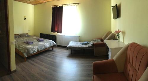 een slaapkamer met een bed, een bank en een stoel bij Mini Hotel Polonyna in Pilipets