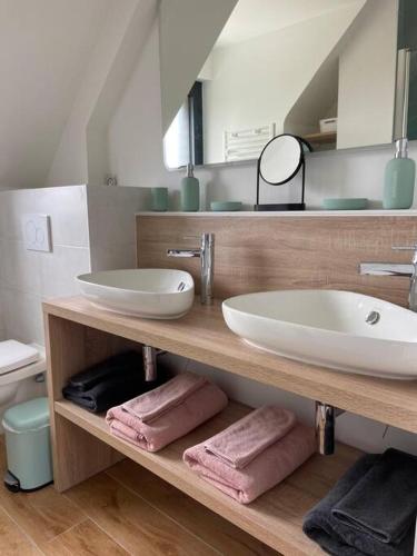 une salle de bain avec deux lavabos sur une étagère en bois avec des serviettes dans l'établissement Longère en pierre - 5 personnes, à Plouhinec
