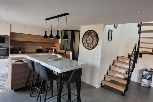 une cuisine avec une table, des chaises et une horloge dans l'établissement Longère en pierre - 5 personnes, à Plouhinec