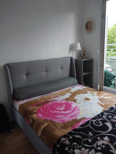 ein Bett mit einer Blumendecke darauf in einem Schlafzimmer in der Unterkunft DANA S HOME in La Courneuve