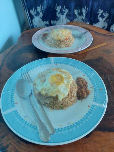 two plates of breakfast food on a wooden table at D'Ru Guest House in Labuan Bajo