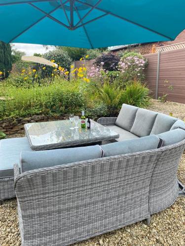 two wicker chairs and a table with an umbrella at The Coach House at Copper Hall in Leominster