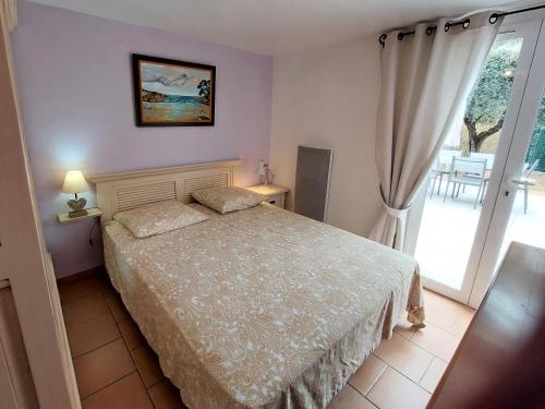 a bedroom with a bed and a large window at GITE LES PINS piscine chauffée jardin privatif climatisation Wifi parking in Peymeinade