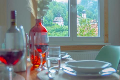 a table with glasses and a bottle of wine and a window at Wellnessoase mitten in Triberg in Triberg