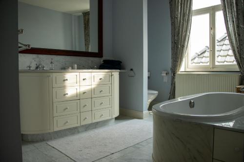 Baño blanco con bañera y lavamanos en B&B Huis Spaas, en Neerpelt