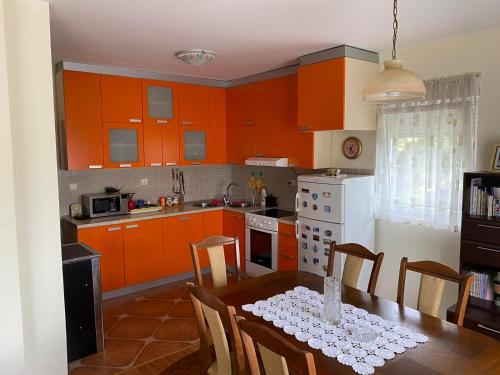 eine Küche mit orangefarbenen Schränken und einem Tisch mit Stühlen in der Unterkunft Vila Frutak in Danilovgrad