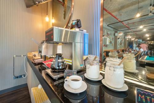 a kitchen with a counter with cups and a coffee maker at Qiu Hotel Sukhumvit SHA Plus in Bangkok