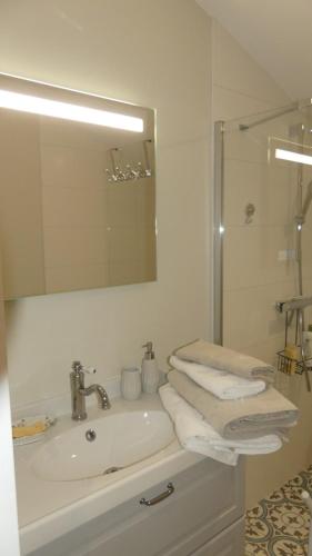 W łazience znajduje się umywalka, lustro i ręczniki. w obiekcie La Petite Lande w mieście Ménil