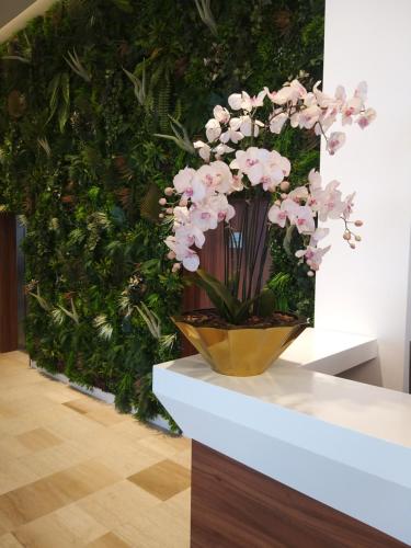 a vase of flowers on a table in front of a green wall at Prenoćište SRBIJA in Surdulica