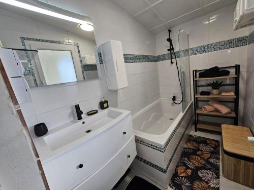 y baño con lavabo blanco, bañera y espejo. en Maison familiale, 3 chambres, jardin et parking privé en Montigny-en-Gohelle