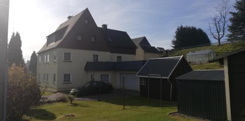 een groot wit huis met een zwart dak bij Ferienwohnung Sonnenblume in Pfaffroda
