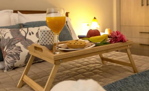 a tray of food and a glass of wine on a bed at Ruby's summer house with spacious garden and free parking in Gavrion