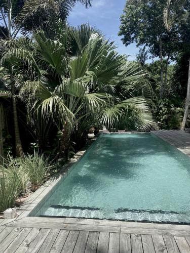 a swimming pool with a wooden deck and palm trees at Soleluna Casa Pousada in Trancoso