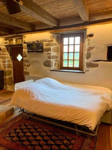 une chambre avec un grand lit dans un mur de pierre dans l'établissement Les Maisons du Bonheur & Balnéo, à Croze