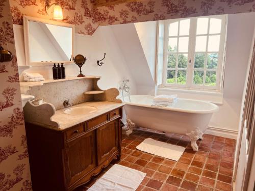 a bathroom with a tub and a sink and a window at Chateau de Villette in Poil