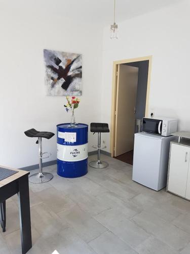 une chambre avec des chaises et un tonneau bleu recouvert d'un vase. dans l'établissement F1 centre ville, à Bohain-en-Vermandois