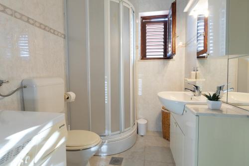 La salle de bains blanche est pourvue de toilettes et d'un lavabo. dans l'établissement Apartman Dugeč, à Kaštela