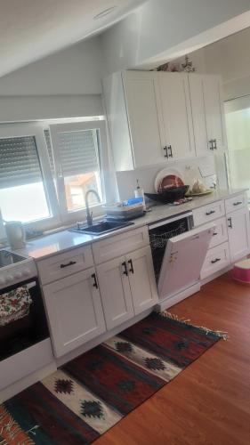 a kitchen with white cabinets and a sink and a rug at Domo I Gago in Sukošan