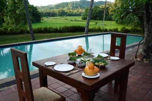 een houten tafel met eten naast een zwembad bij Raddegoda Walawwa Kurunegala in Ridigama